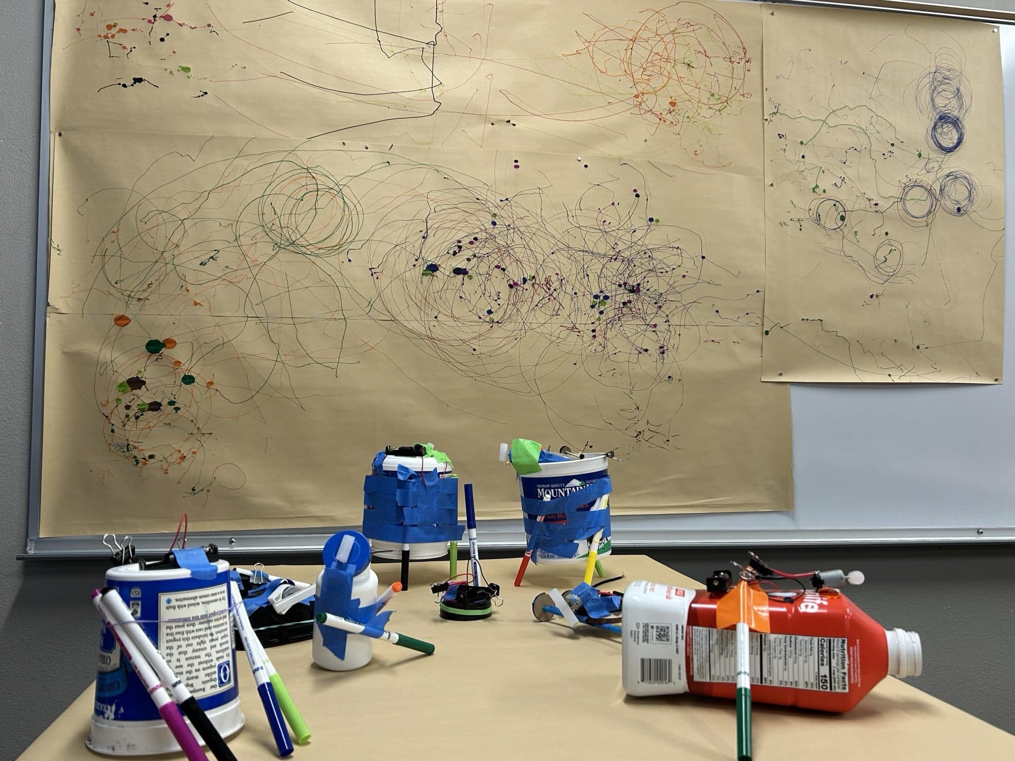 A scribble bot drawing circles in marker on butcher paper