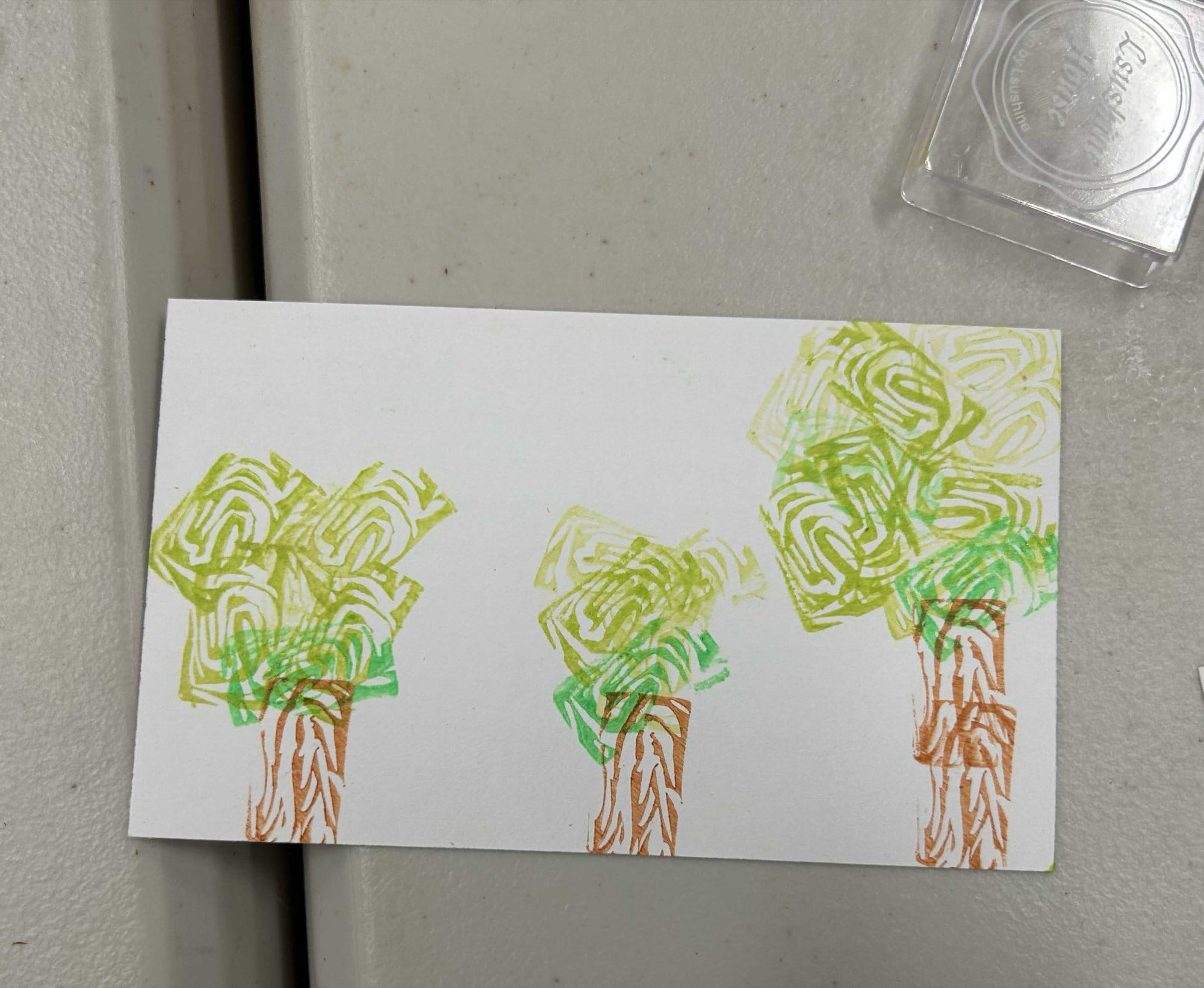 A block-printed card with trees in green and brown ink